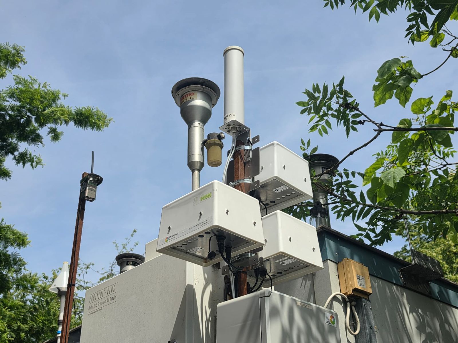 Outdoor monitoring equipment and sampling instruments mounted on a pole among trees
