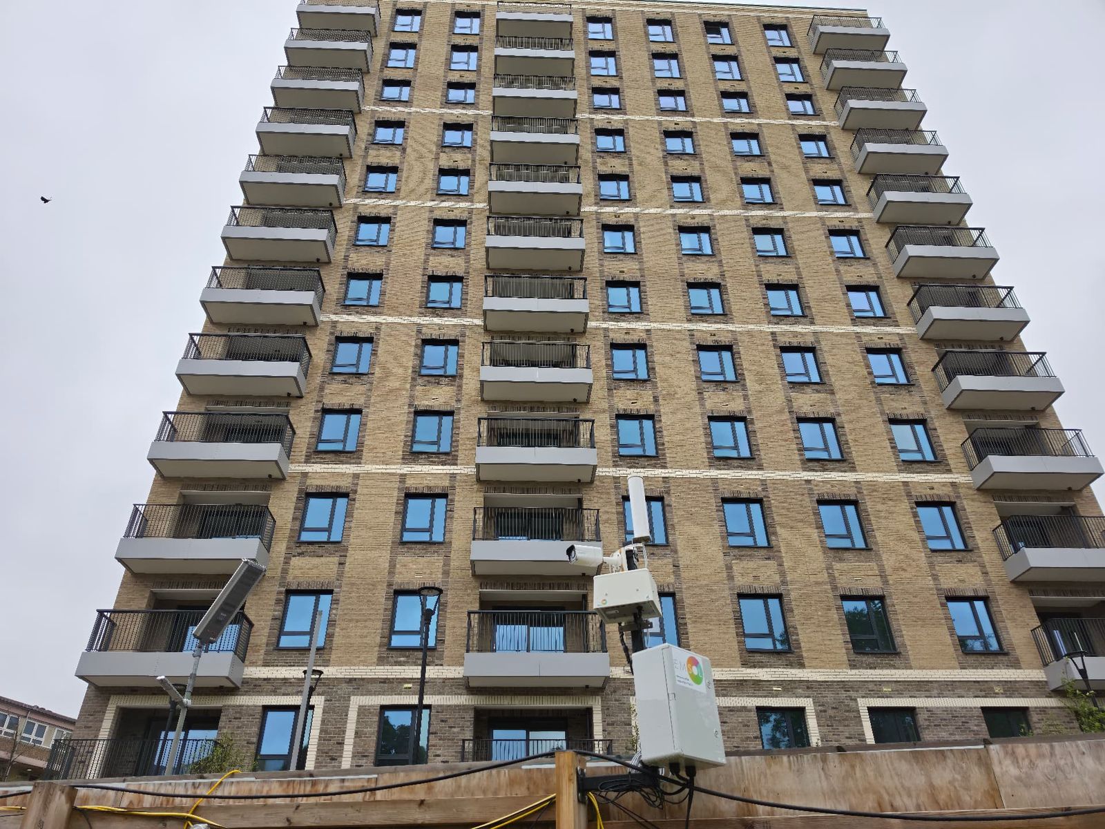 Monitoring unit with solar panel installed in front of a tall residential building