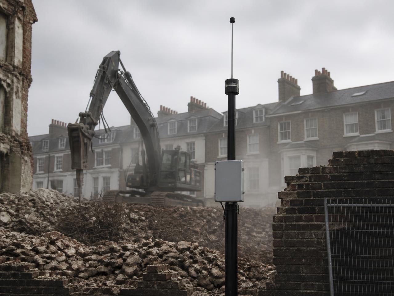 Monitoring mast installed beside a demolition site next to a historic brick terrace